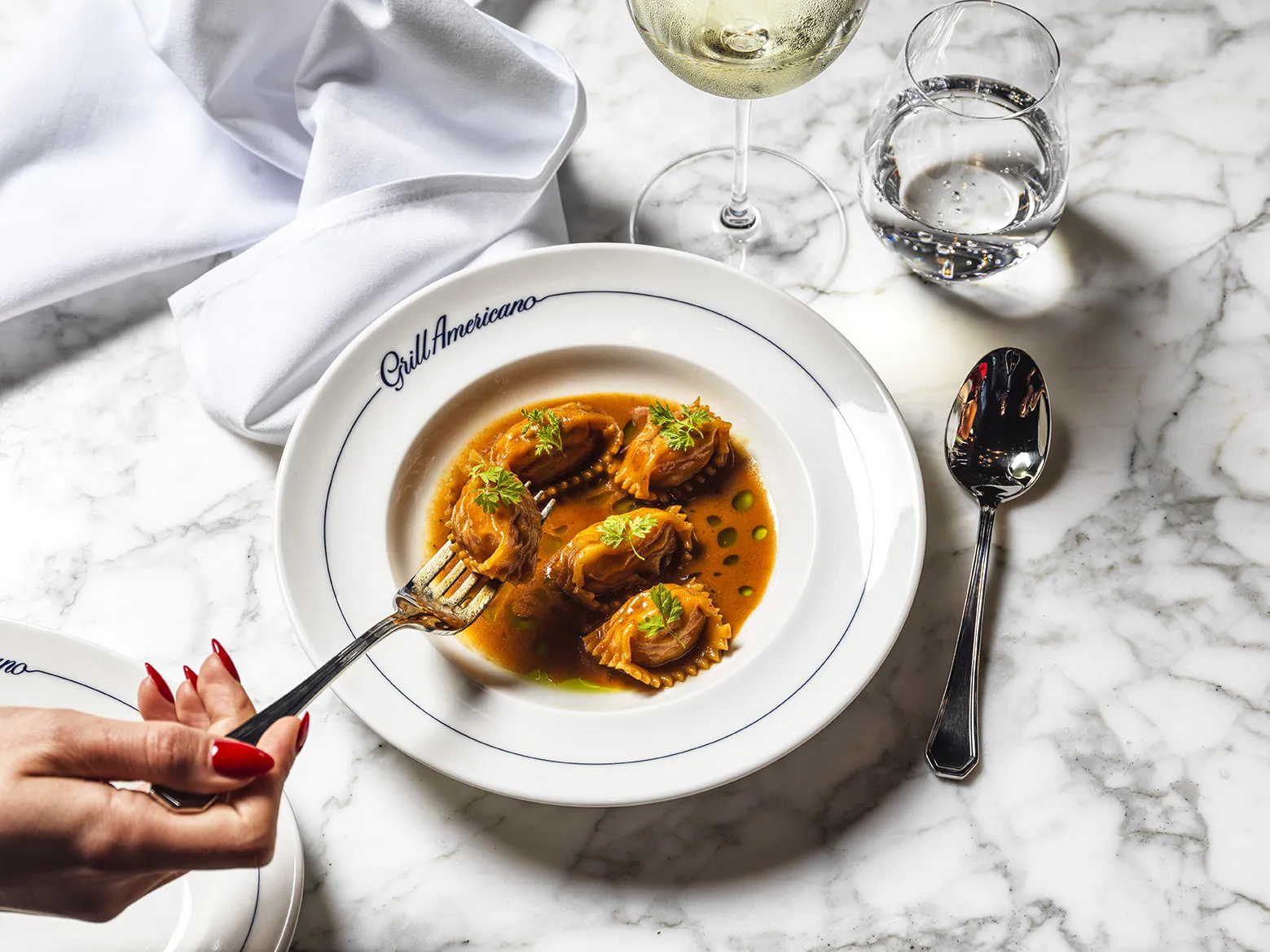 A lobster filled pasta with bisque and fresh herbs in a bowl