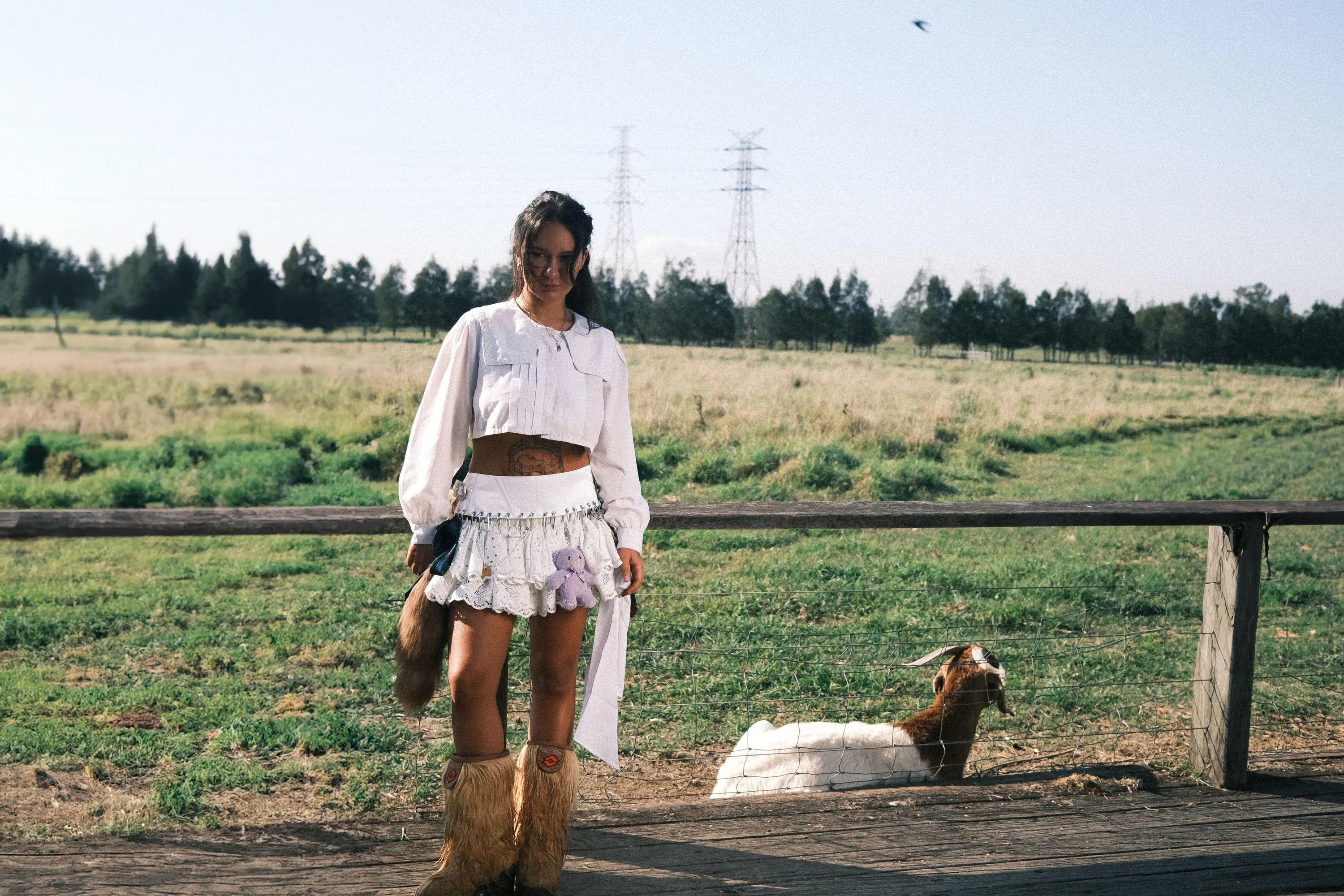 Singer Mallrat in a white outfit next to a goat.