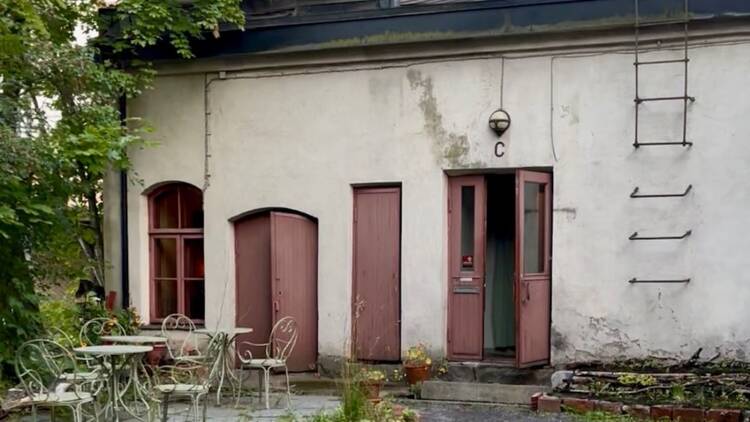 Tunnelmallinen sisäpiha Tampereen Apaja-ravintolassa, vanha kiviseinä, punaiset ovet ja romanttinen terassikalustus.