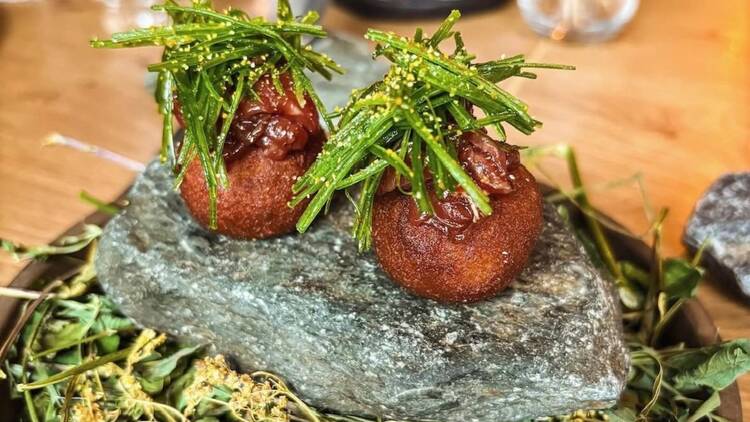 Ravintola Kajon annos Tampereella: rapeat pallot täytettynä lihalla ja koristeltu tuoreilla yrteillä kivellä tarjoiltuna.