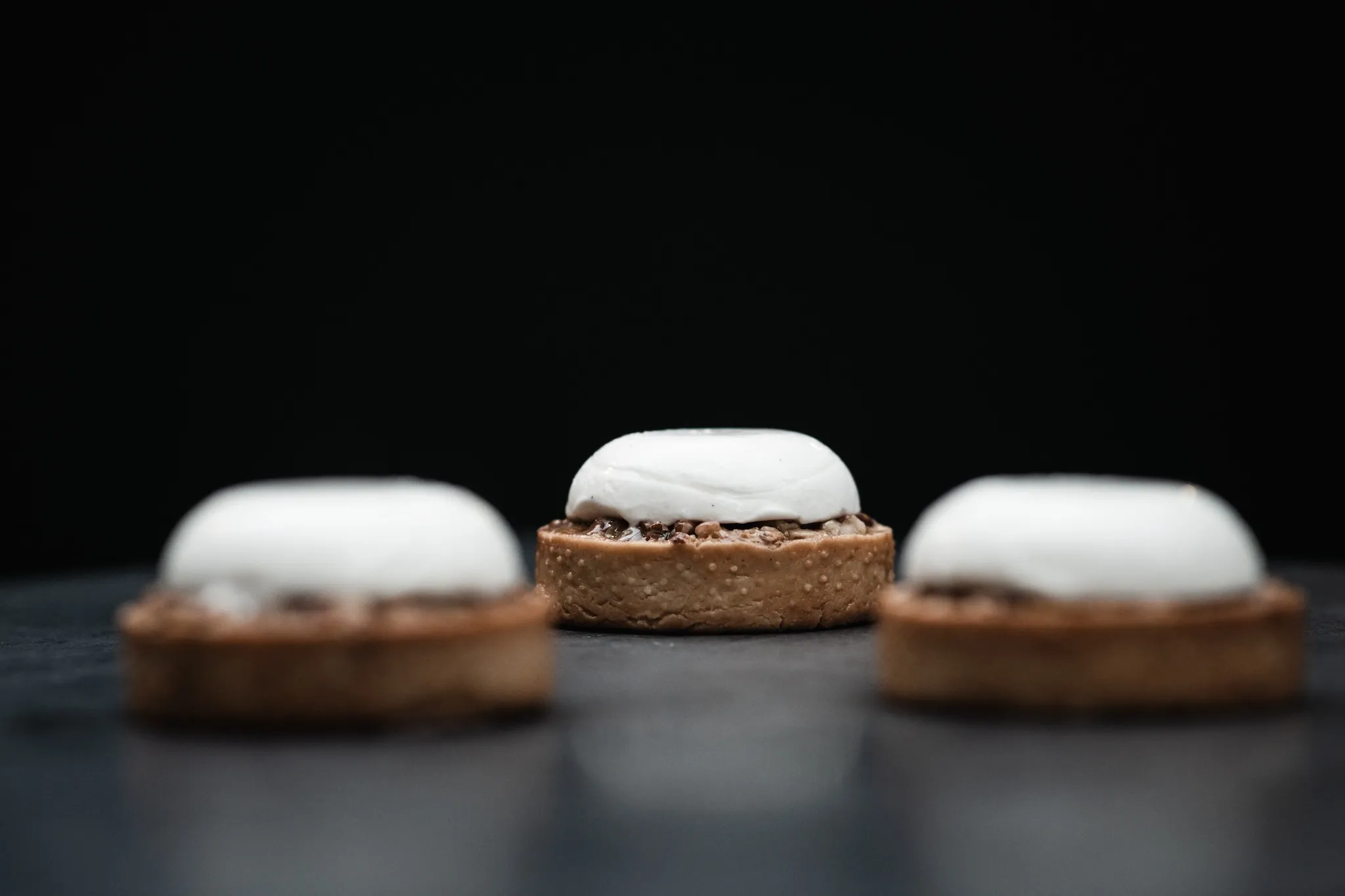 Three pecan tarts on a black table