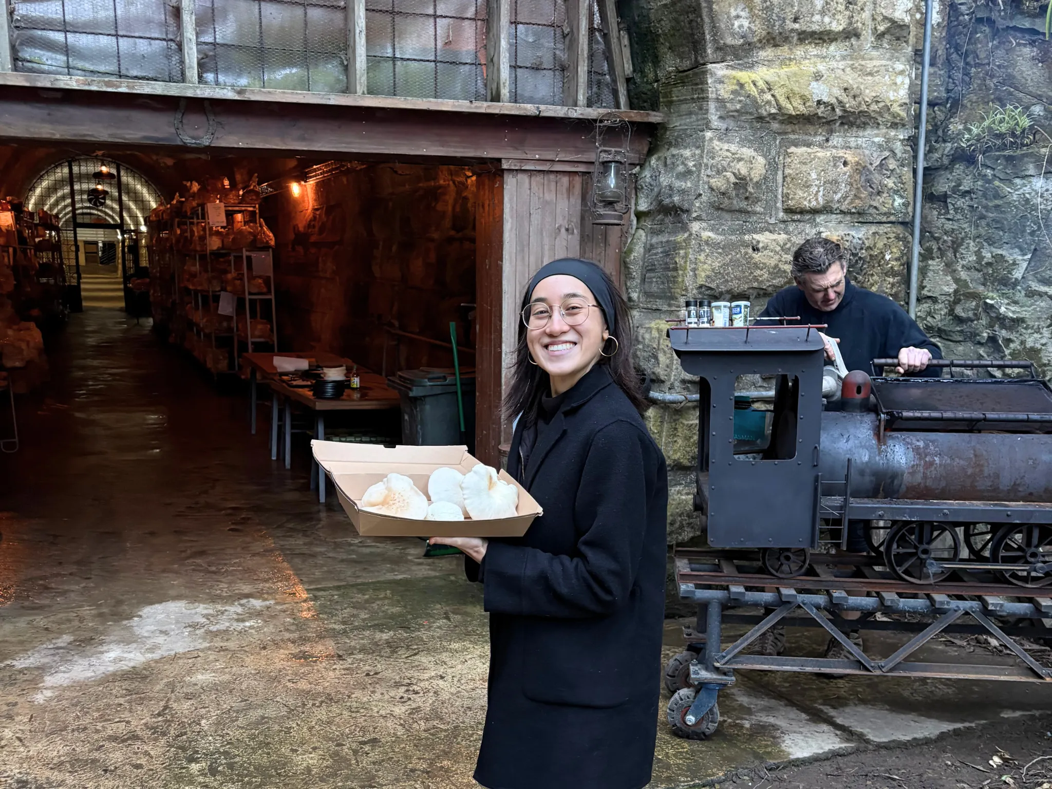Girl smiling in front of tunnel with tray of mushrooms