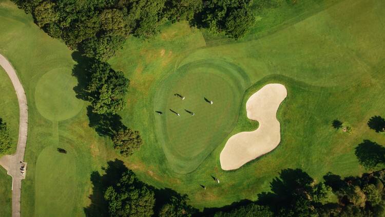 Aerial drone shot of a scenic golf course with players on the green