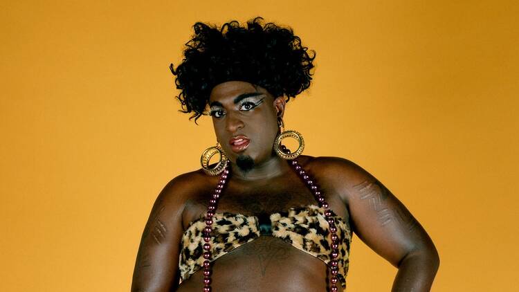 Portrait by Catherine Opie of a Black man in drag wearing a leopard print bikini in front of a yellow backdrop Portrait by Catherine Opie of a Black man in drag wearing a leopard print bikini in front of a yellow backdrop