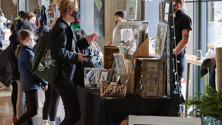 People shopping at a pop up art table People shopping at a pop up art table