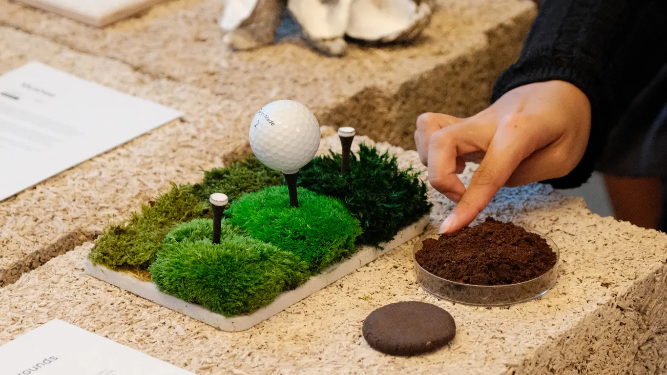 A person touching a dish of coffee grounds.