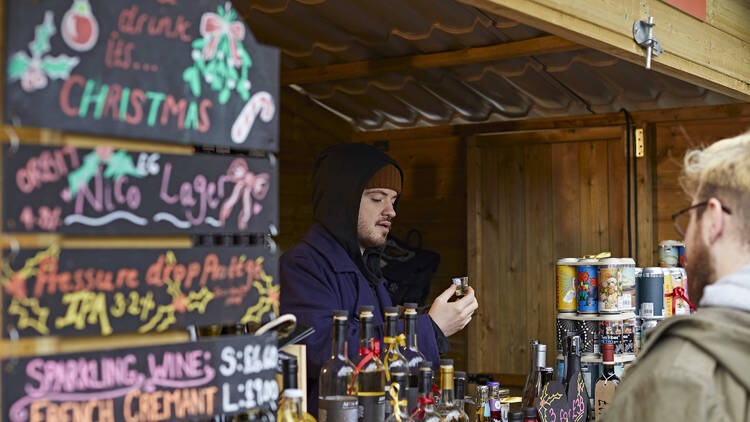 Photo of a man working at a small chalet in a christmas market at a mulled wine stand Photo of a man working at a small chalet in a christmas market at a mulled wine stand