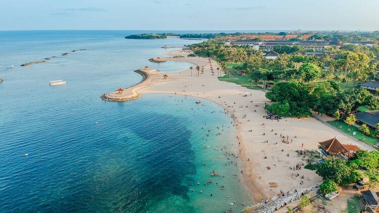 Sanur Beach Bali Indonesia Aerial drone view of Holiday In Sanur Beach, Bali, Indonesia with ocean, boats, beach, villas, and people.