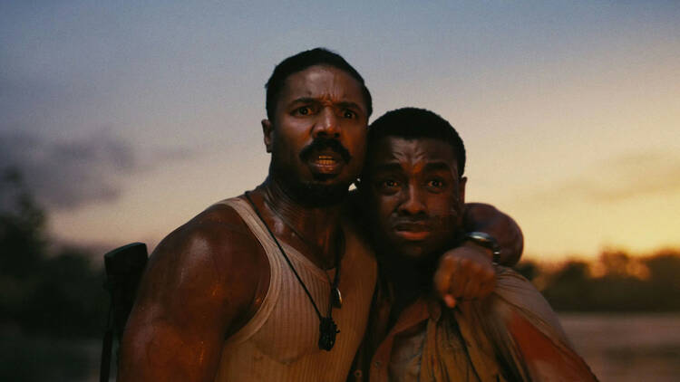 Film still of 'Sinners' where two men embrace while the sun rises behind them