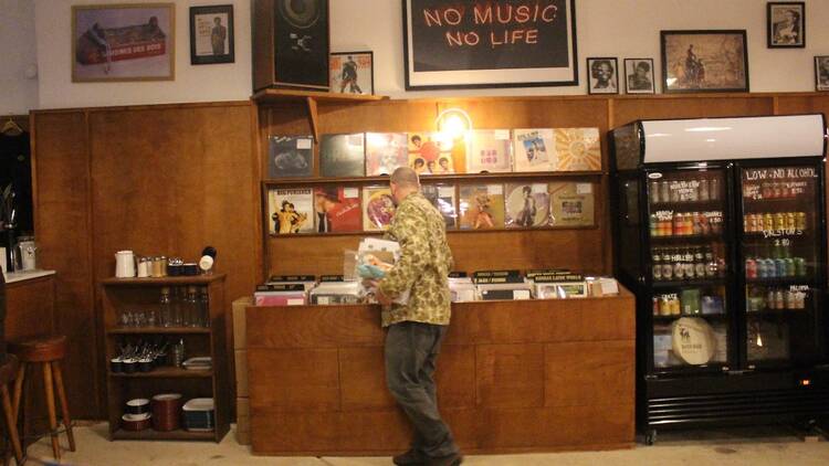 Man dressed in jeans and a printed jacket picks up vinyl records in a music store 
