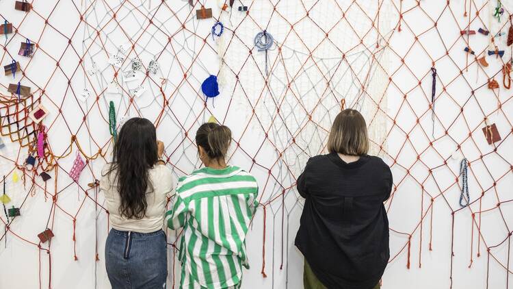 Patrons at Intuit Art Museum admire an artwork. Patrons at Intuit Art Museum admire an artwork.