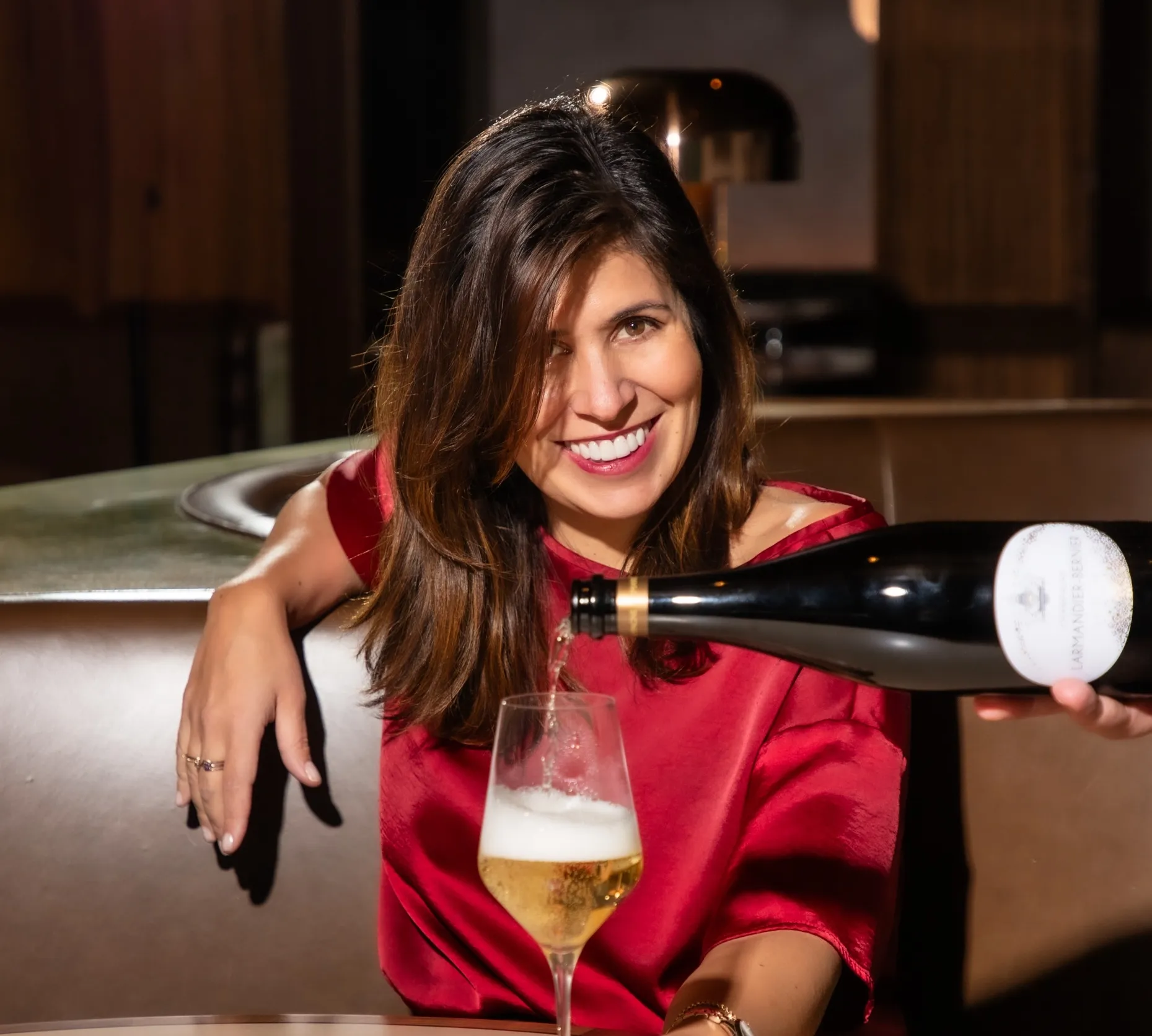 Andreina Mayobre sitting a booth with a glass of wine in front of her