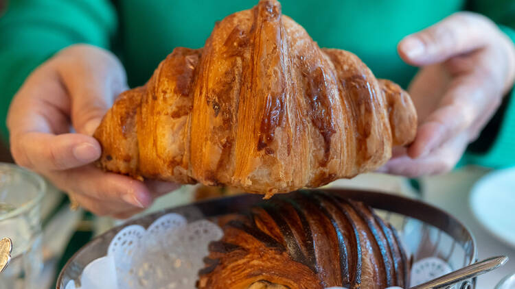 Vihreäpaitainen nainen ojentaa croissantia Vihreäpaitainen nainen ojentaa croissantia