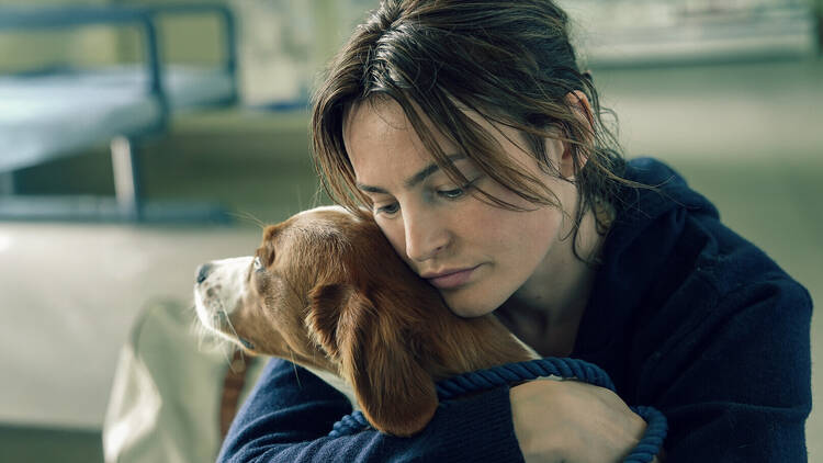 A film still of a woman hugging her dog