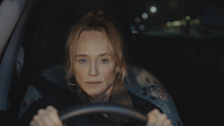 A film still of a woman driving a car