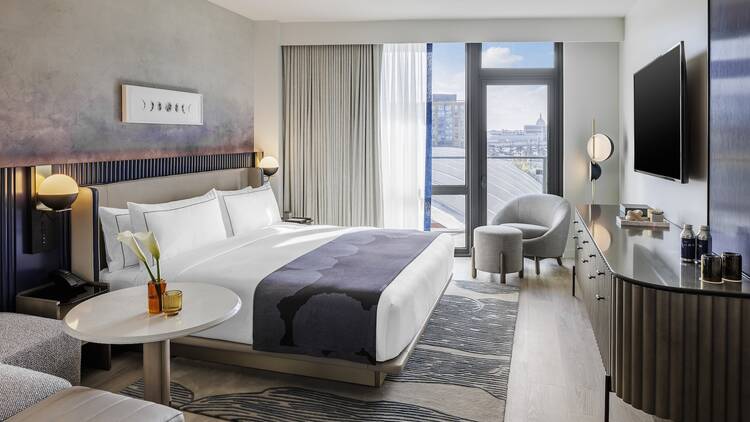 A hotel room with a white bed and purple accent decor. A hotel room with a white bed and purple accent decor.