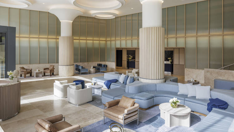 The lobby of a hotel with blue banquettes and white columns. The lobby of a hotel with blue banquettes and white columns.