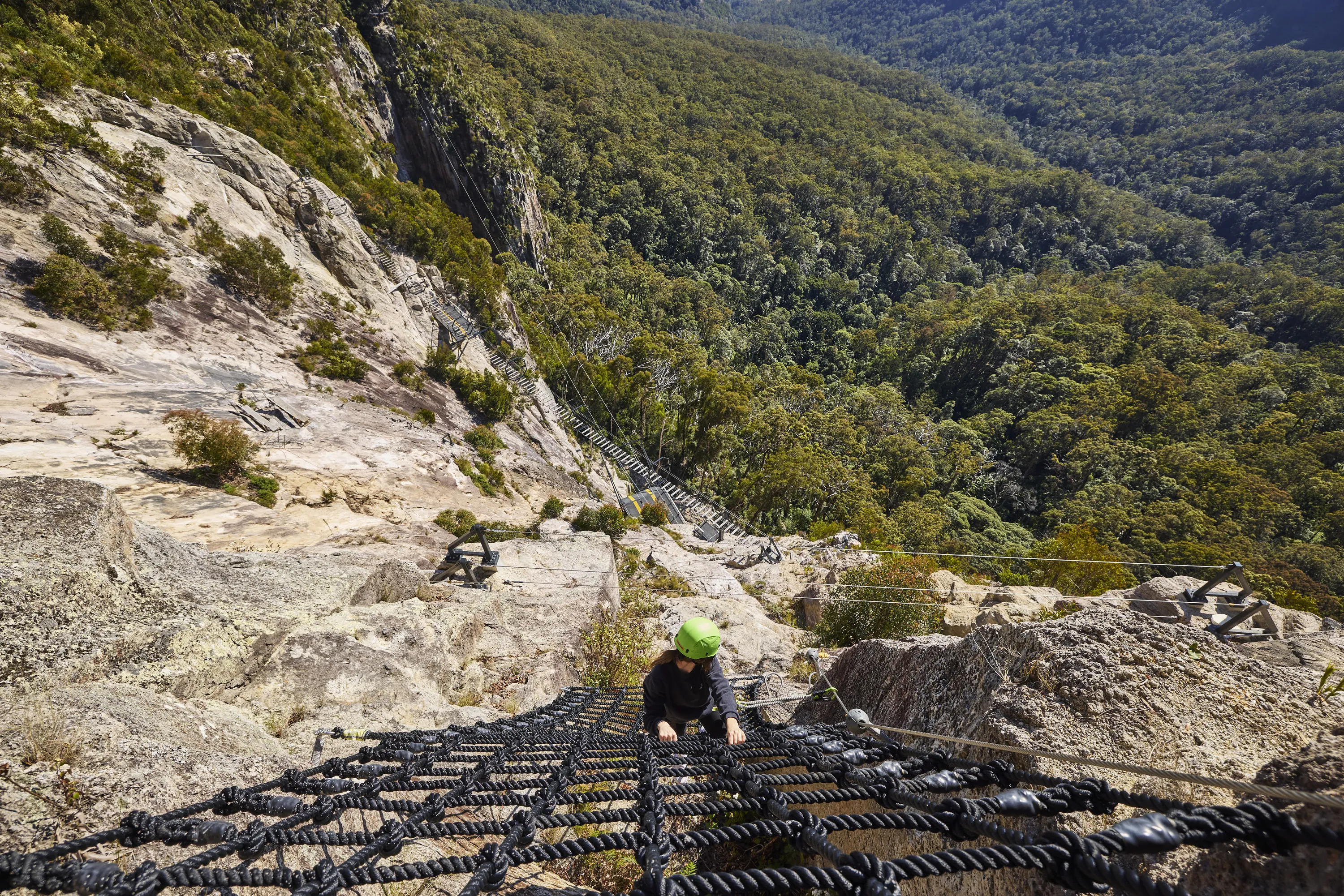 Girl climbing adventure rope at cliff park