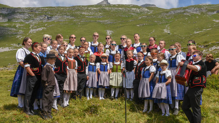 People wearing traditional clothes yodeling at Engstlenalp on the Swiss alps