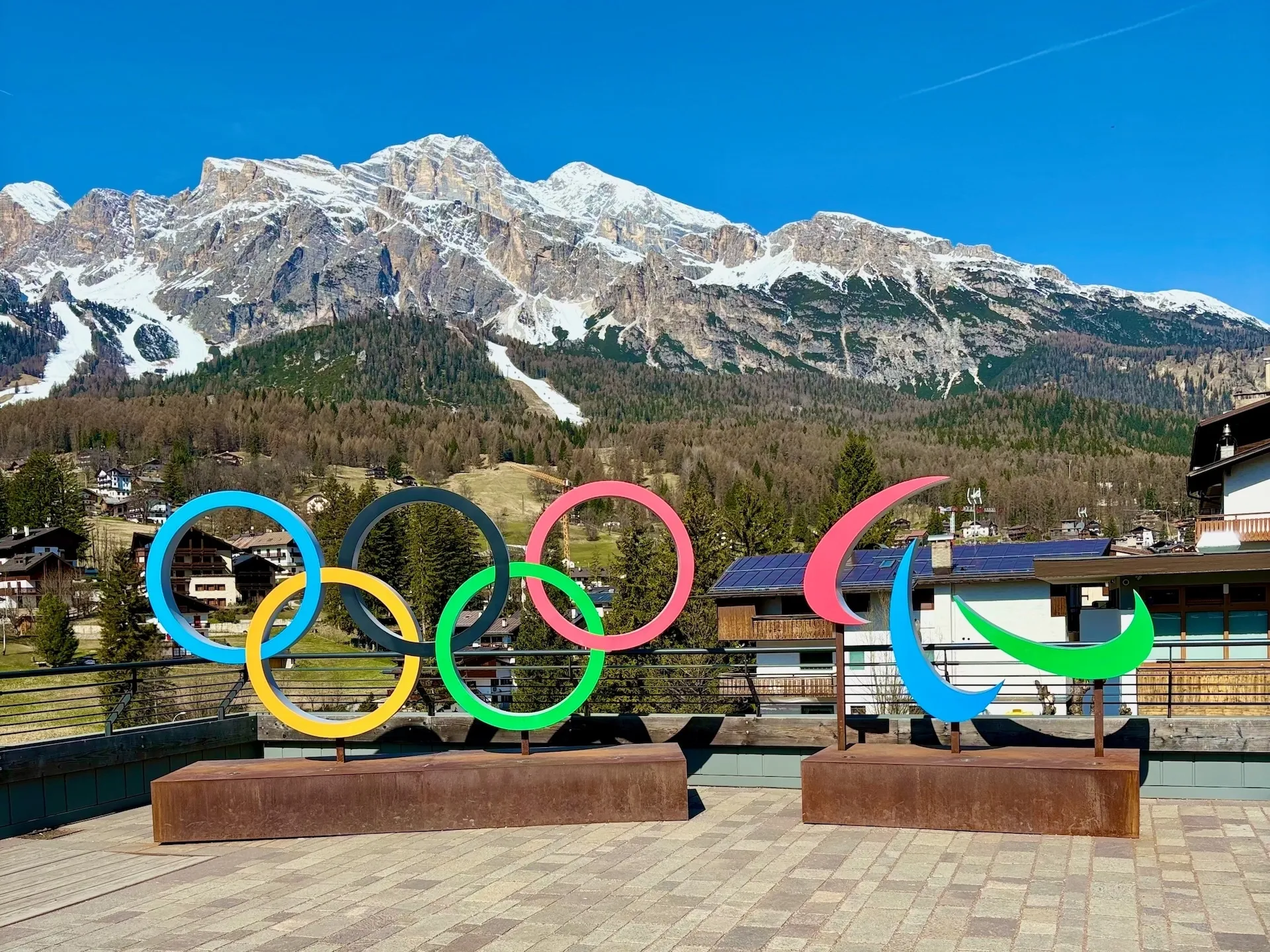 Cortina d'Ampezzo, Italy - April 16 2025 winter olympics or 2026 milano cortina olympic rings and logo on display in front of the mountains with snow on top of it. The Tofane Dolomite massif