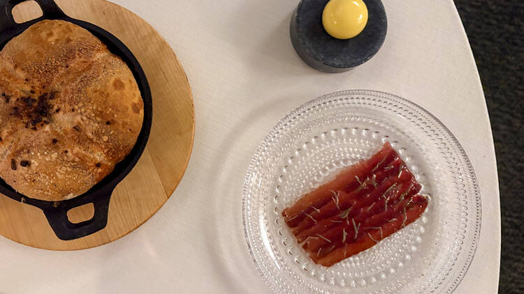 Leipää ja kylmäsavustettua poroa lautasella ravintola Olon pöydällä