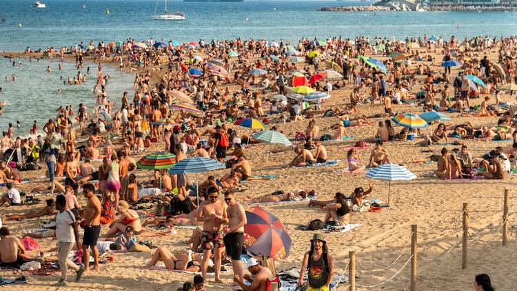  A crowd of people on the sands of Barceloneta Beach in Barcelona Spain