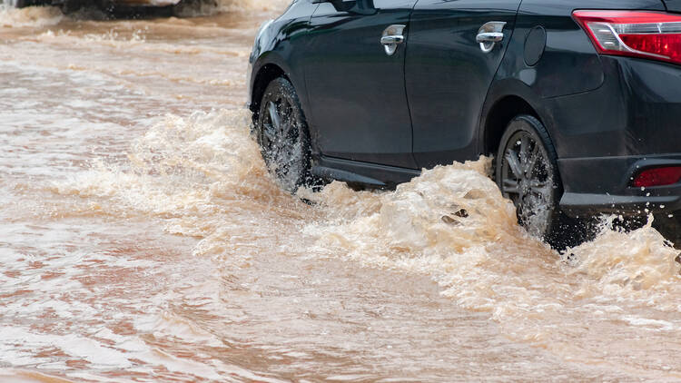 Muddy rain from a heavy rainy season flooded main roads connecting the district, making it difficult for cars to pass through and causing engine failures, in motion, car insurance concept, in motion.
