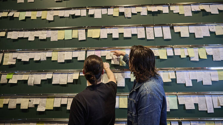 People looking at a wall of restaurant dockets.
