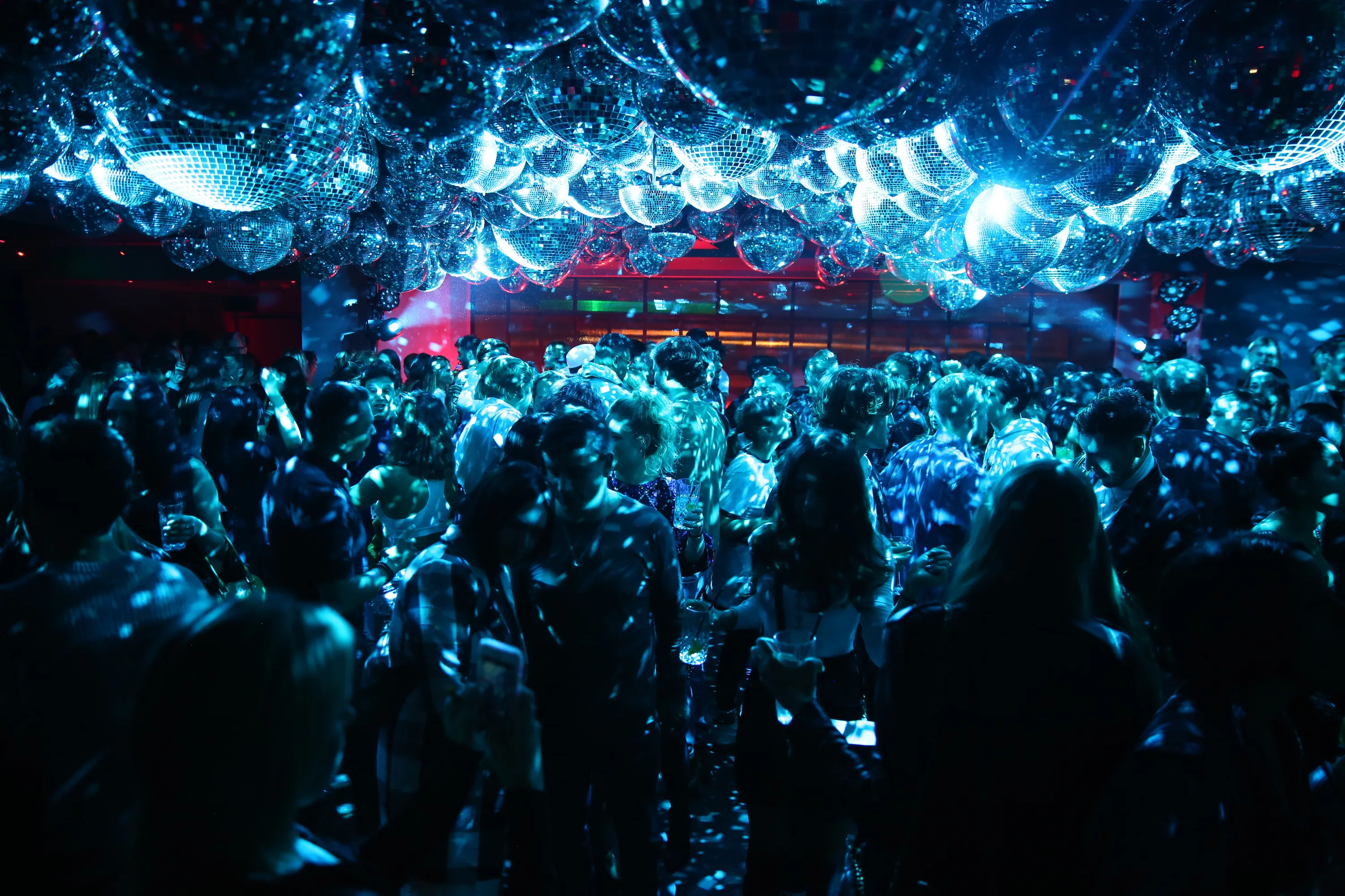 Disco balls above a dance floor filled with people.