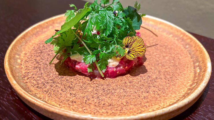 Tartarpihvi, jonka päällä on yrttejä ja kukkia koristeena