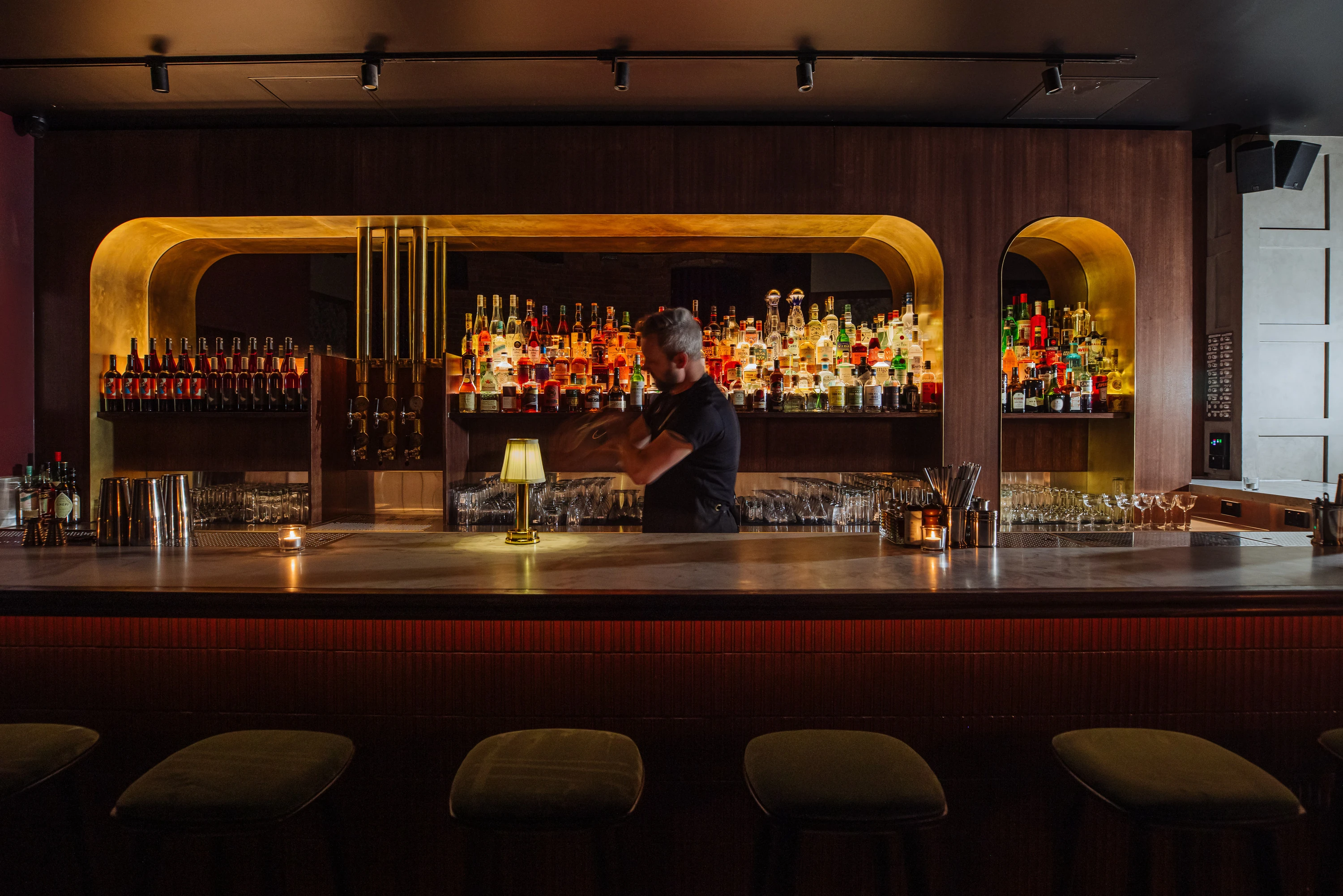Bartender shaking a cocktail behind the bar at Death and Co.