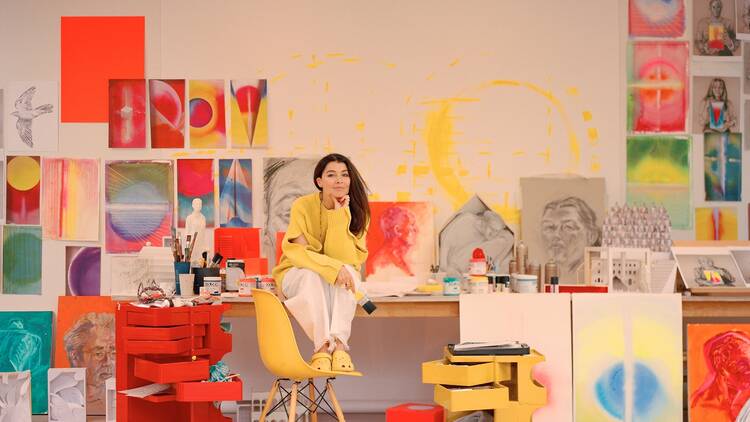 Es Devlin in her London studio Es Devlin sits on a desk in her London studio surrounded by colourful sketches