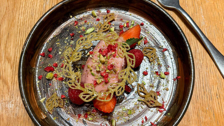 Jälkiruoka Tampereen Berthassa, vaaleanpunainen annos marjojen kanssa tummalla lautasella.