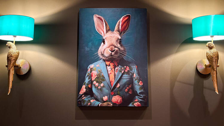 Taulu ravintola Berthan seinällä Tampereella: pupua esittävä muotokuva, molemmin puolin seinävalaisimet.