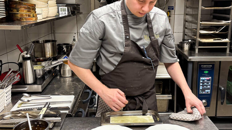 Annos viimeistellään ravintola Berthan keittiössä Tampereella, kokki työskentelee kahden lautasen äärellä ravintolakeittiössä.