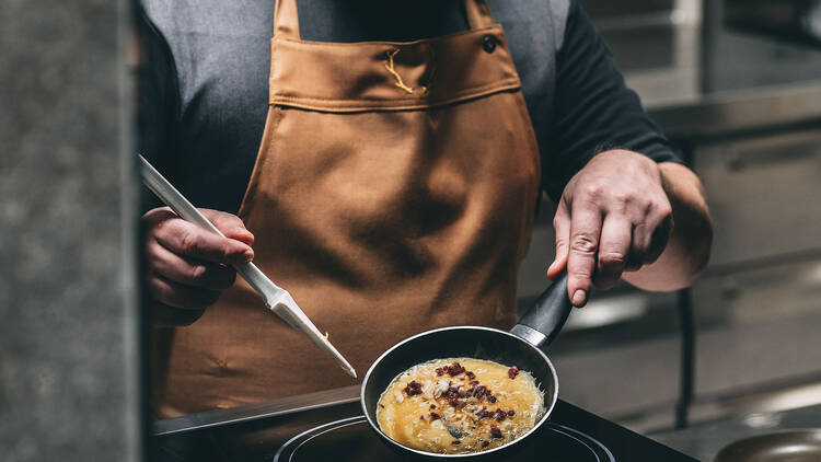 Kokki valmistaa lämmintä annosta asiakkaalle Saivo Kitchen & Bar of Momentsissa Tampereella.