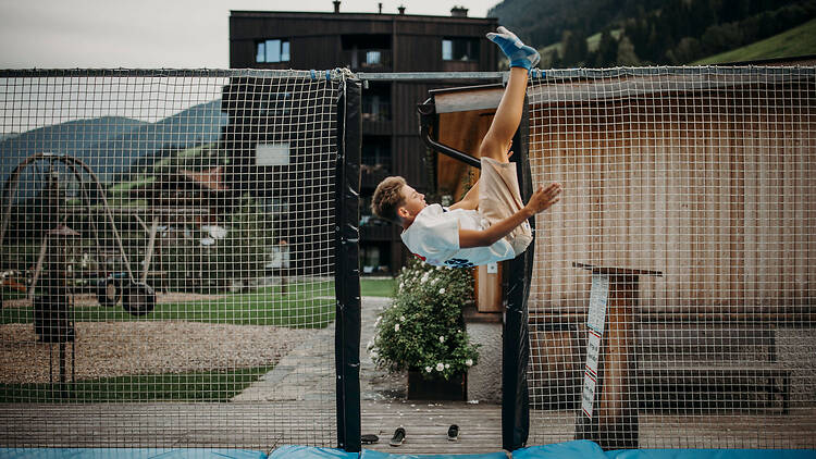 A boy does a somersault on a trampoline at Familien Natur Resort Moar Gut