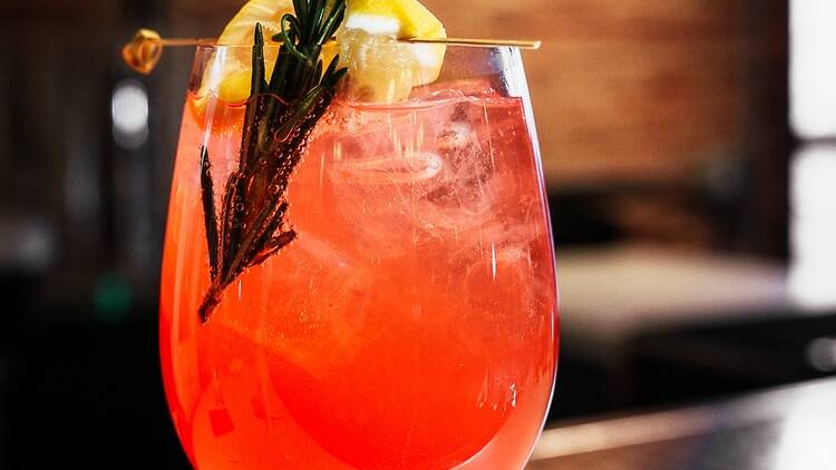 A spritz with a sprig of rosemay and a lemon