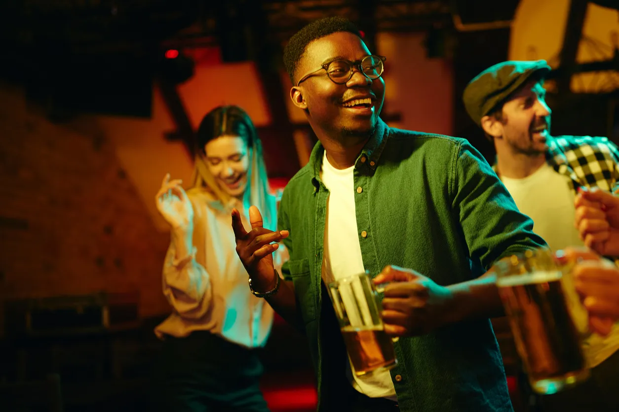 Young happy black man having fun while dancing with his friends in a bar at night.