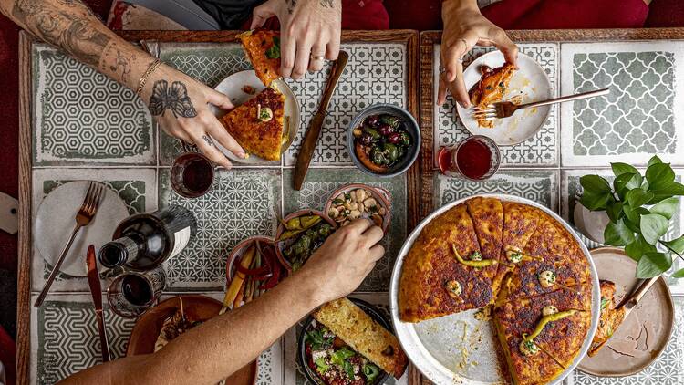 Hands eating multiple tapas dishes