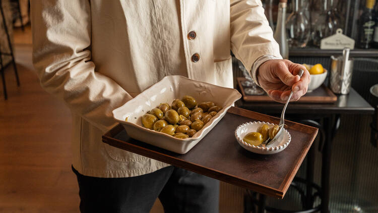 A waiter holding a tray with olives.