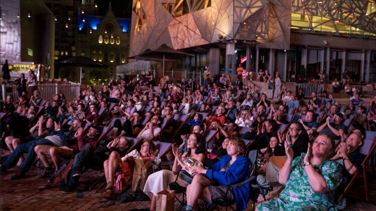 People sitting in an outdoor cinema at Fed Square.