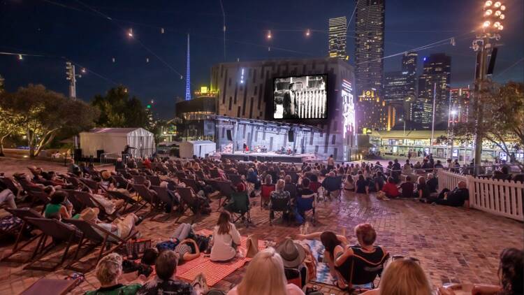 People sitting in an outdoor cinema at Fed Square.