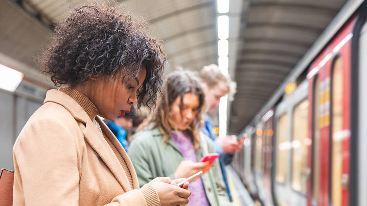 Commuters with phones at a London Underground station