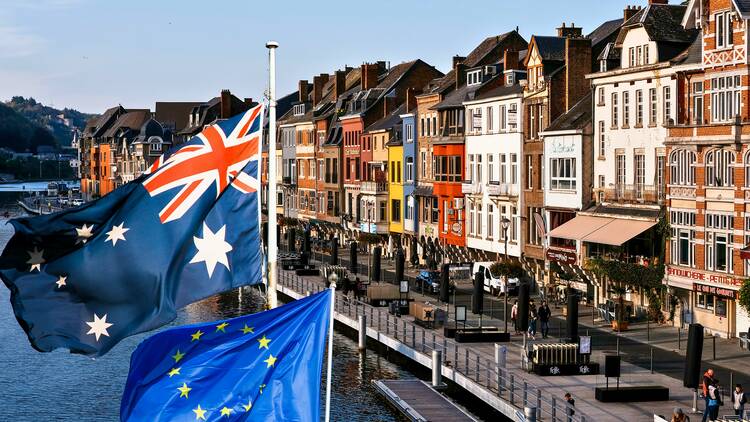 Side of a european city with colorful brick houses next to the river with two flags