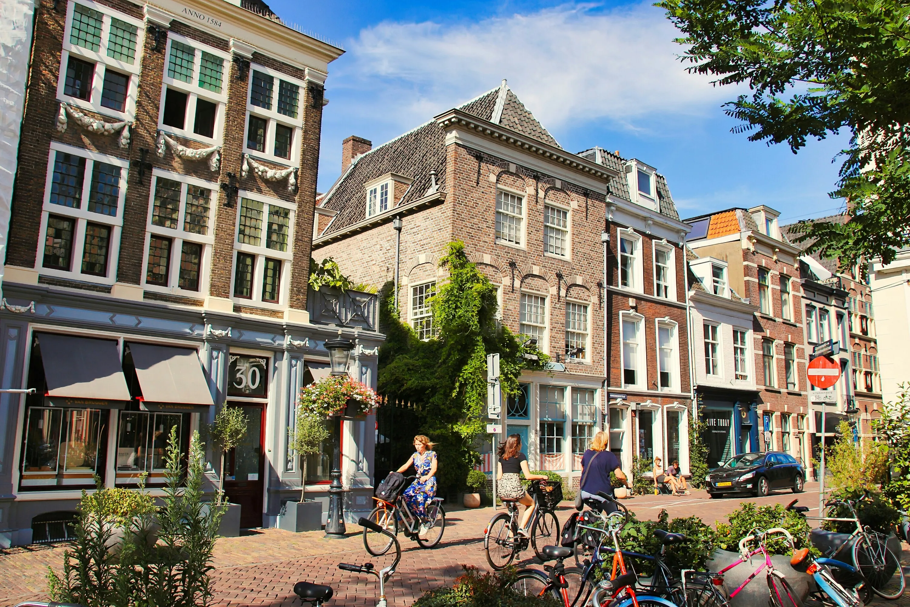 A group of people riding bikes down a street next to tall buildings