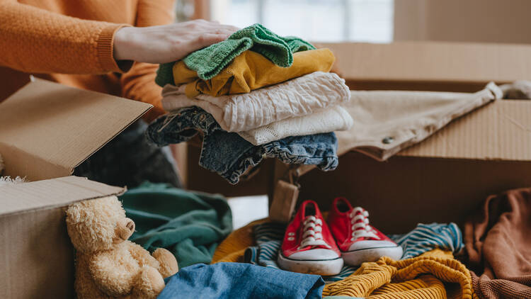 2192191401 Close-up of woman sorting an old out-of-use kid toy, clothes and shoes in box for charity or converting discarded materials. Upcycling concept.