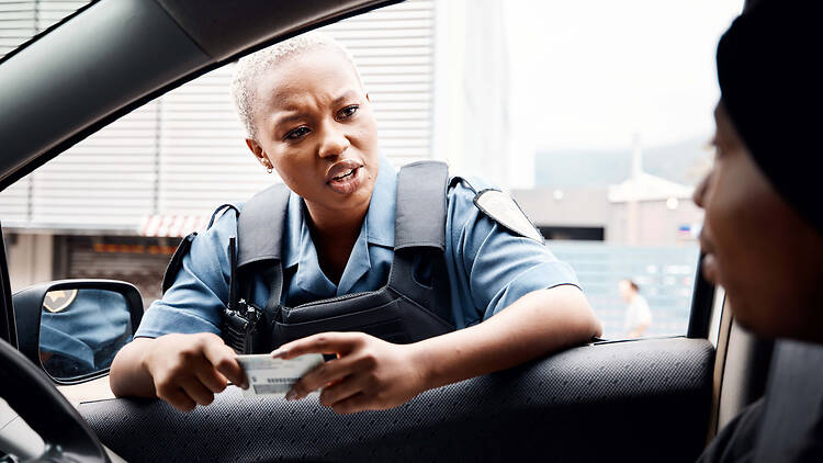 Police officer talking to driver on the road holding driver's licence 