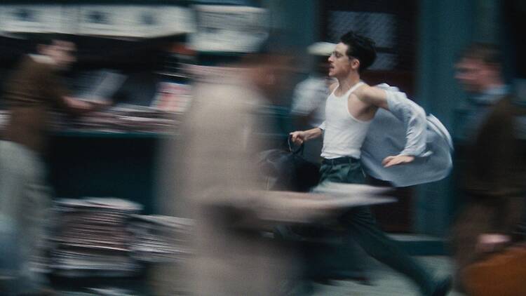 Timothee Chalamet juoksee paitahulmuten väkijoukon keskellä elokuvassa Marty Supreme