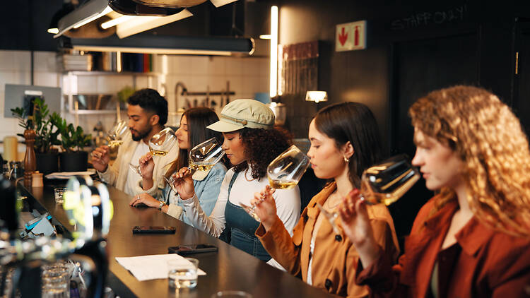 2239908384 Restaurant, friends and smell glass at wine tasting for experience, flavor preparation and bonding. Night, people and alcohol aroma at pub venue for quality testing, weekend break or social gathering